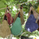 Brand new brightly coloured wine skins hanging across a rope in the trees