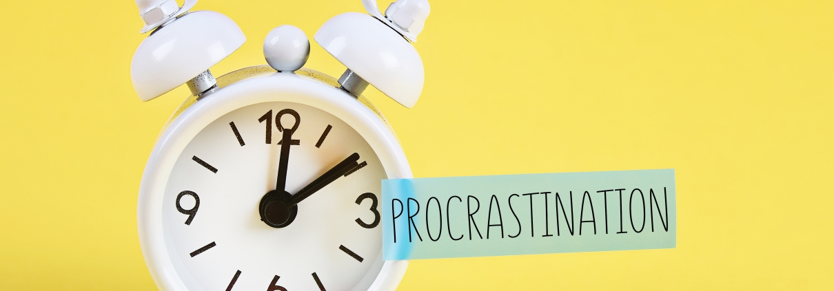 Procrastination, delay and urgency concept. White alarm clock with text procrastination.