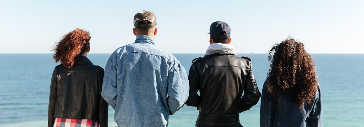 Back view image of a group of friends standing outdoors near the beach. Are they unequally yoked?