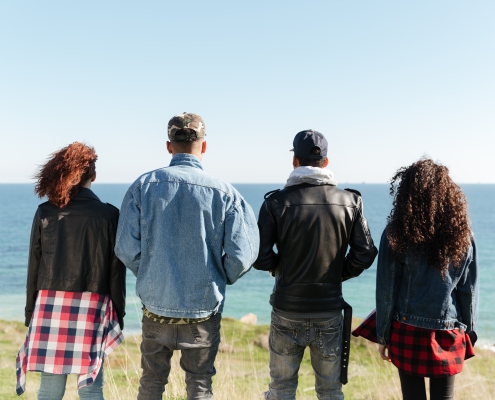 Back view image of a group of friends standing outdoors near the beach. Are they unequally yoked?