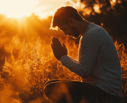 A man with a loyal heart towards God sits cross-legged in a serene field, hands clasped in prayer, soaking in the warmth of the setting sun amidst tall grass.