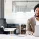 African-American young businessman working on his laptop in a contemporary office space with glass partitions on the backdrop. Concept of business and technology, bunner, panoramic view