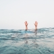 cropped-hands-person-emerging-from-sea-against-clear-sky