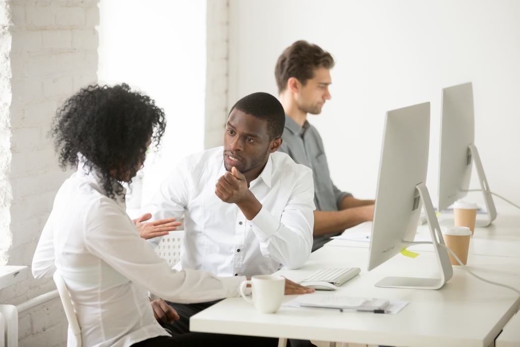 Serious african colleagues discussing project together at workplace, black coworkers talking solving business problem in multiracial office, afro american teammates displaying character traits
